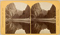 Two black and white landscape photographs of three figures on the shore of a body of water with mountains behind.