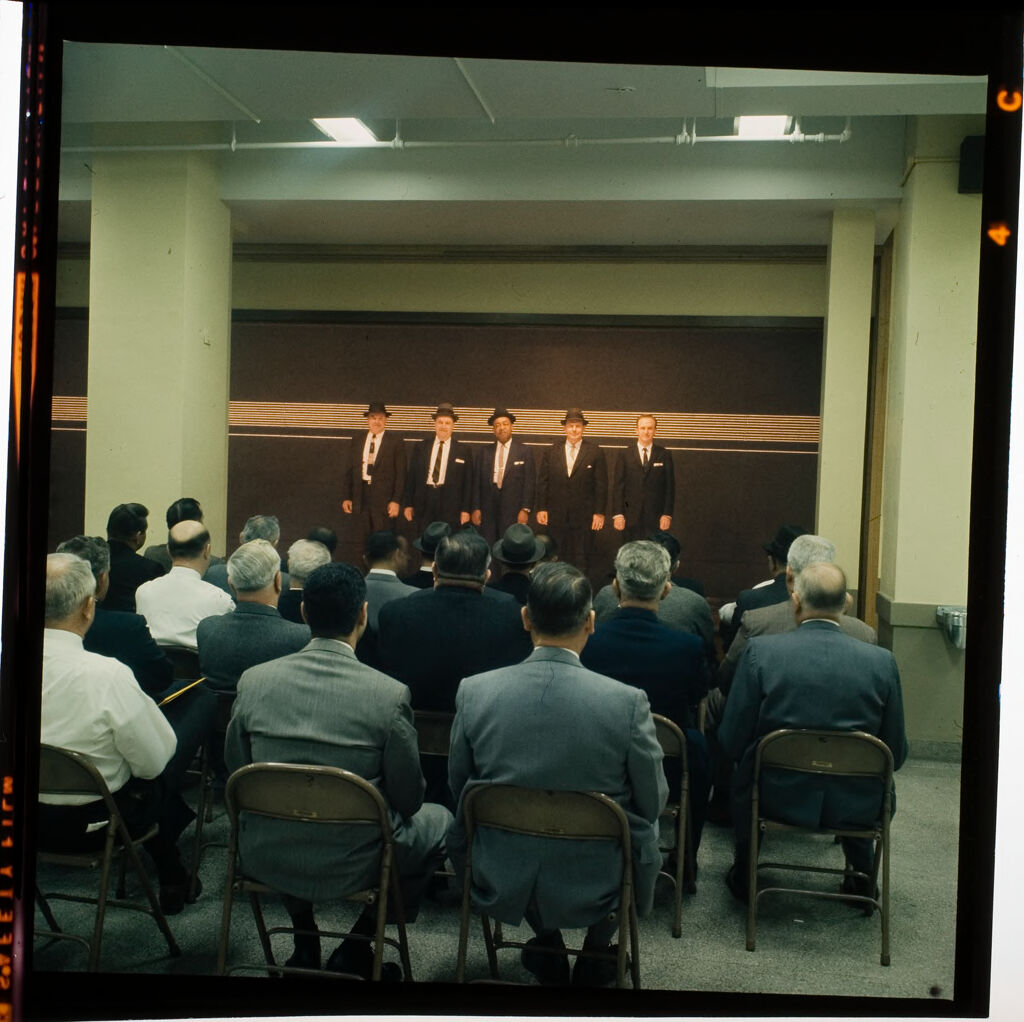 Untitled (Men In Suits Standing In Police Line-Up, Audience Watching)
