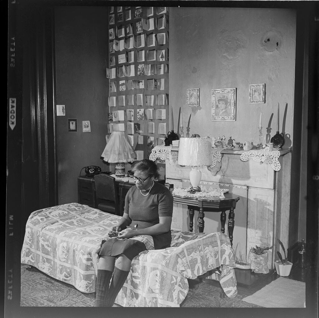 Untitled (Woman Sitting On Bed Inside Small House)