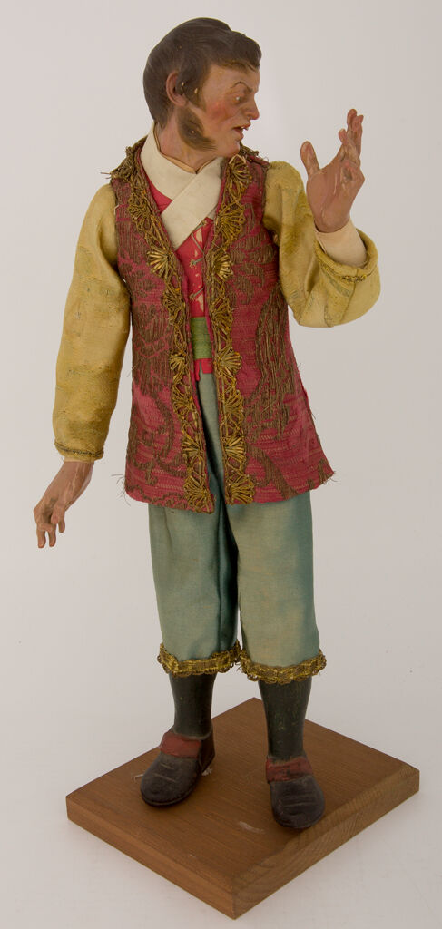 Man With Red Vest With Metallic Embroidery, Gold Sleeves, And Aqua Pants