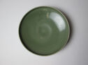 A circular dish shown from above. It is dark green and has a thin lip.