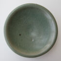 A circular dish shown from above. It is green colored with many irregular cracks in the glaze.