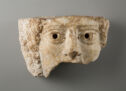 A fragmentary marble mask depicts the face of a person from mid-forehead to just below the nose.