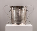 A silver cup with two thin looping handles.