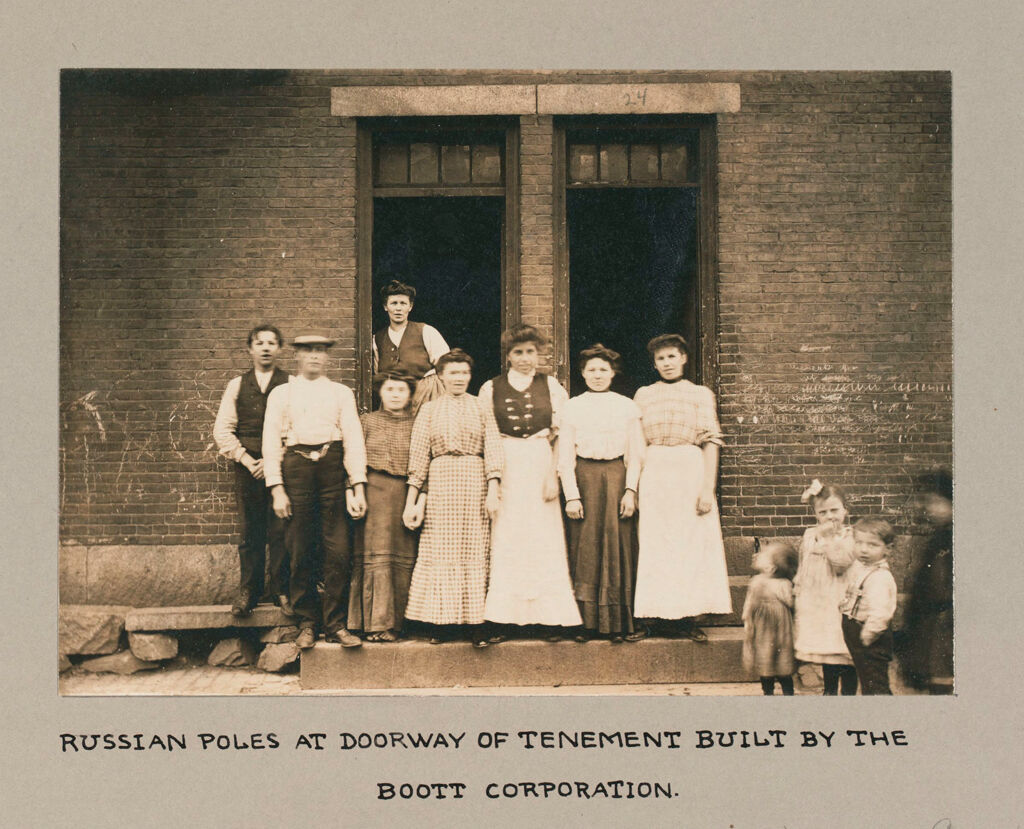 Housing, Conditions: United States. Massachusetts. Lowell. Tenements In French, Greek And Polish Districts: Environment After Immigration, Perpetuation Of European Standards In America: Russian Poles At Doorway Of Tenement Built By The Boott Corporation.