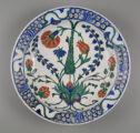A plate seen from above which is decorated with blue, green, and orange floral designs. 