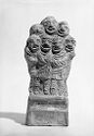 A black and white image of a terracotta sculpture depicting a clustered group of seven standing people. All of their faces have large smiles on them and are close together. Their arms are around each other.