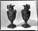 Two single-handled black vessels with figures holding the spouts.
