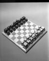 A chess set with pieces in light and dark wood on a gray and white felt board.