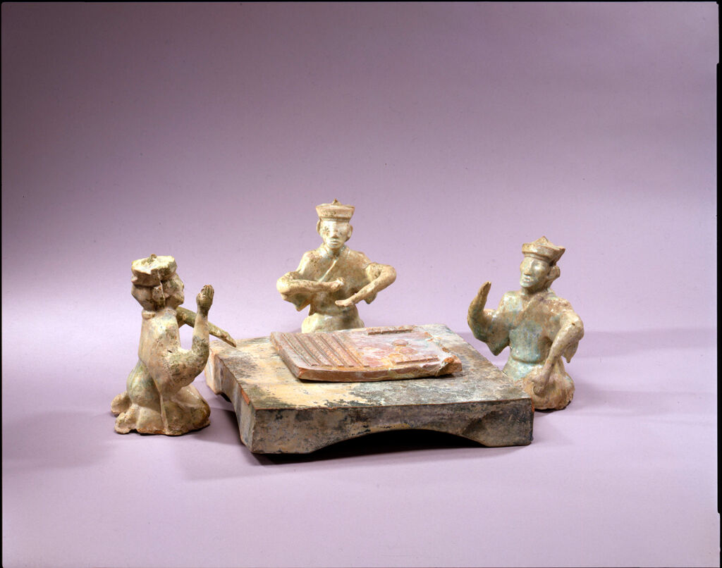 Three Capped Men Kneeling Around A Low Table And Playing 'Liubo'