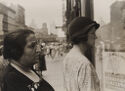 A black and white photograph of two women in a city landscape.