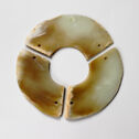 Greenish gray jade disk cut into three pieces with two drilled holes in each segment.