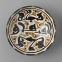 Bowl with large black letters and bird shapes surrounded by dot decoration