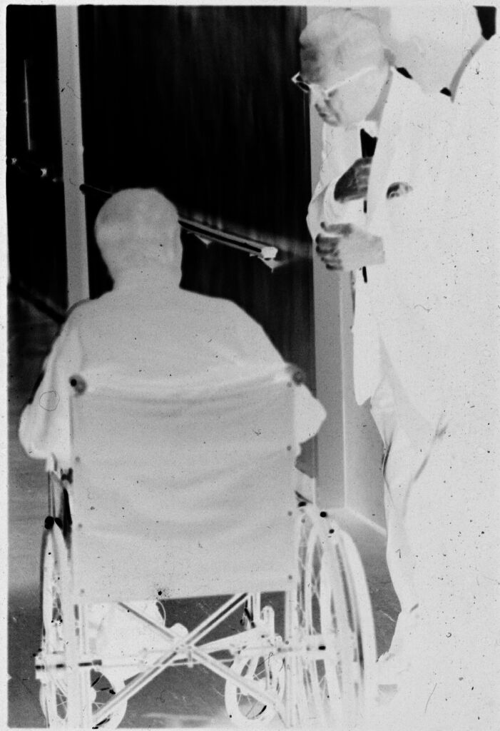 Untitled (Two Doctors With Patient In Wheelchair In Hallway)