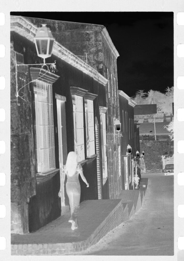 Untitled (Woman Walking On Sidewalk In Front Of Stone Buildings)