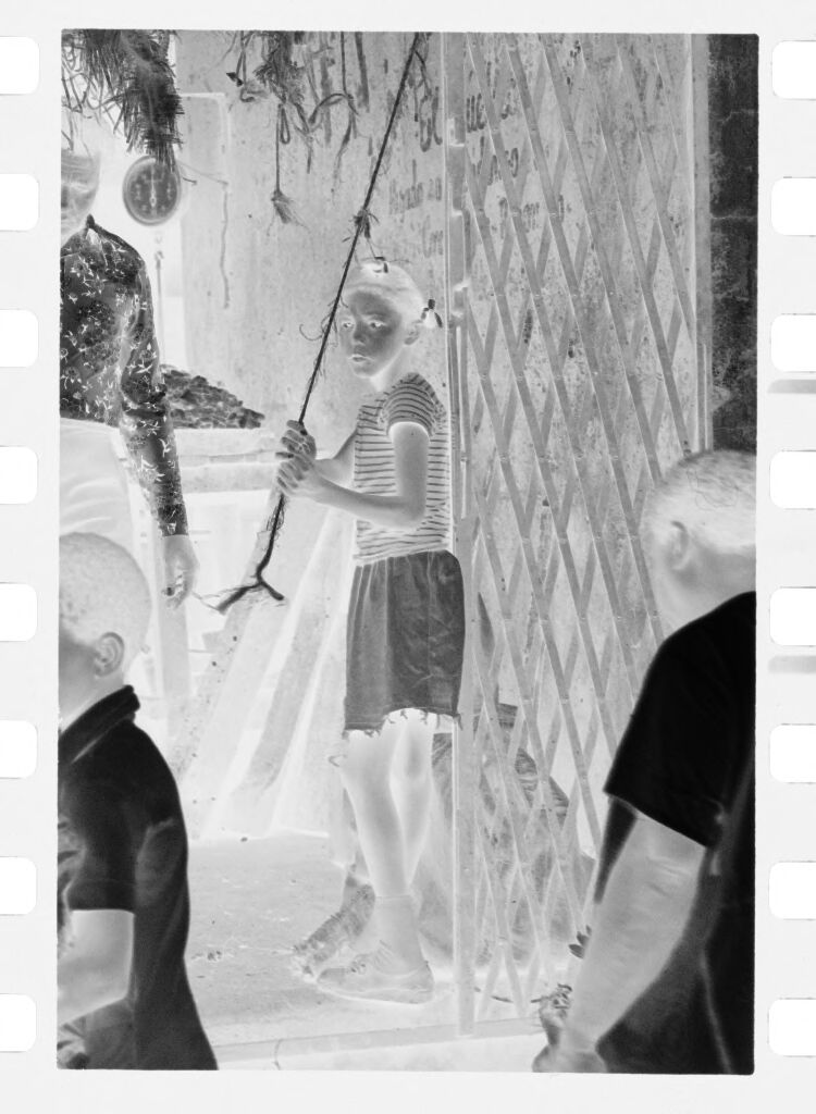 Untitled (Girl Pulling Rope Attached To Gate In Front Of Market Stall)