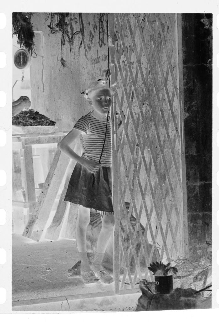 Untitled (Girl Leaning Against Gate In Front Of Market Stall)