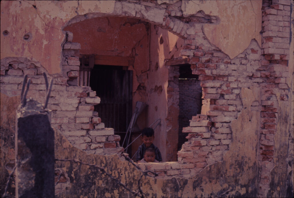 Untitled (Young Boy Standing Inside Damaged Building Visible Through Hole In Wall, Hue, Vietnam)