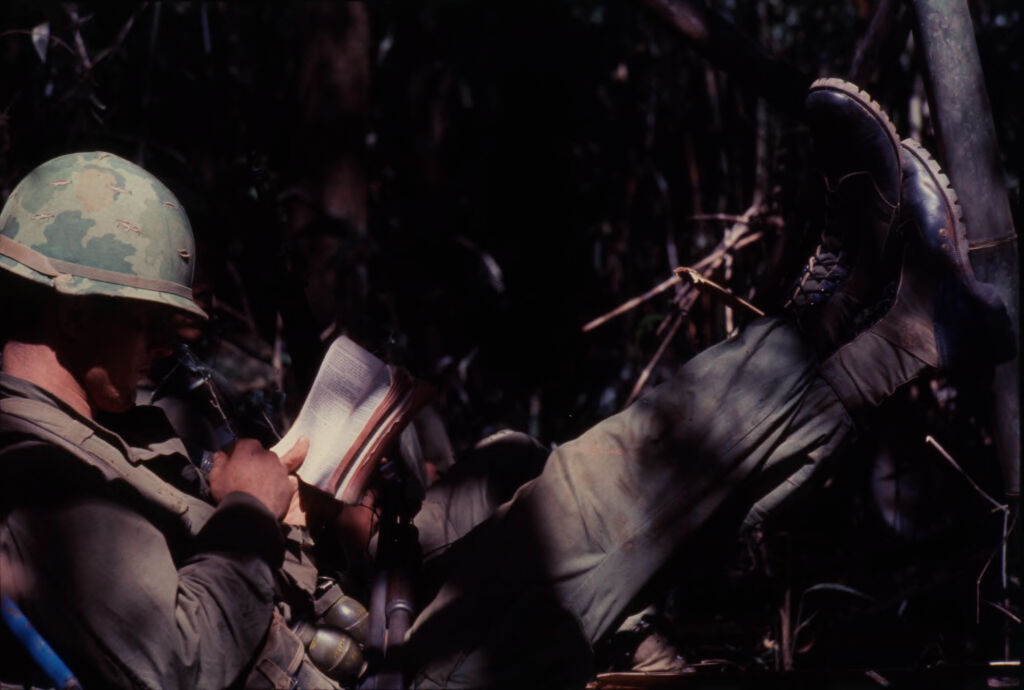 Untitled (Camouflaged Soldier Sitting In Jungle Reading During Fighting In Central Highlands Near Dak To, Vietnam)