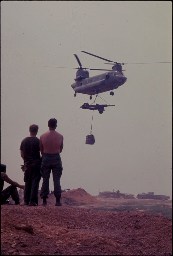 Untitled (Soldiers Watching Chinook Helicopter Lifting 105Mm Howitzer, Vietnam)