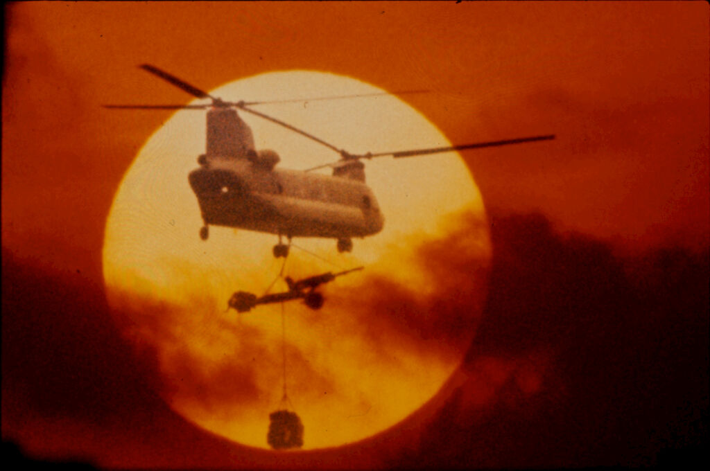 Untitled (Chinook Helicopter With Lifting 105Mm Howitzer Silhouetted Against Sun And Low Clouds, Vietnam)
