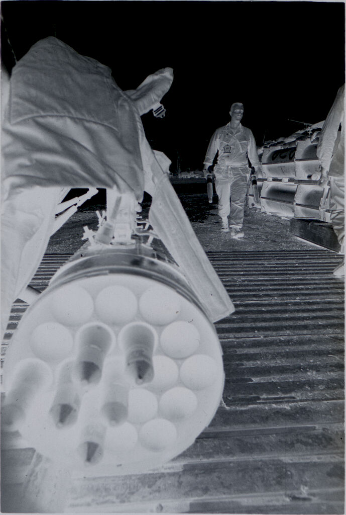 Untitled (Large Rounds Of Ammunition In Cylindrical Storage Unit With Soldier In Background Carrying Two More Rounds, Vietnam)