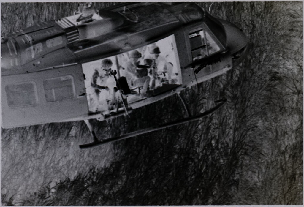 Untitled (Aerial View Of Helicopter Flying Over Field With Soldiers Seated In Open Side, Vietnam)